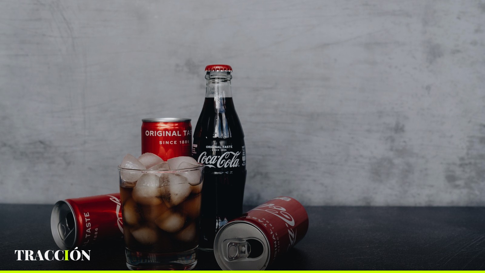 Latas y botella de Coca-Cola junto a un vaso con hielo